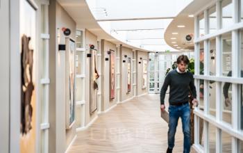 Gehurkte man met laptop loopt door moderne, goed verlichte gang van kantoorruimte op Arlandaweg 92 in Amsterdam Sloterdijk.