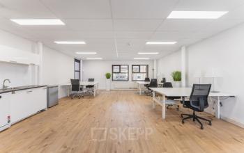 Open, lichte kantoorruimte op Arlandaweg 92 in Amsterdam Sloterdijk met houten vloer, meerdere bureaus en stoelen. Geschikt voor kantoorruimte huren.