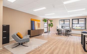 Ruime kantoorruimte huren in Amsterdam Sloterdijk aan Arlandaweg 92 met moderne meubels, bureaus en een grote plant, geschikt voor werk en vergaderingen.