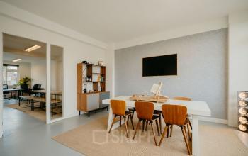 Modern ingerichte kantoorruimte op Overtoom 141 in Amsterdam West met strakke meubels en een grote monitor aan de muur.