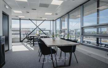 Moderne kantoorruimte te huur in Amsterdam West met grote ramen voor natuurlijk licht, voorzien van tafel en stoelen voor vergaderingen.