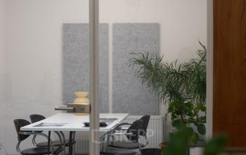 Vergaderruimte in Amsterdam West met moderne inrichting; glazen wanden, grote tafel, zwarte stoelen en enkele planten. Kantoorruimte huren op Hondiusstraat 7H biedt een frisse werkomgeving.