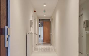 Ingang van een kantoorpand aan de Hondiusstraat 7H in Amsterdam West, een moderne ruimte die uitnodigt tot kantoorruimte huren met heldere verlichting en strakke muren.