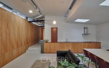 Moderne kantoorruimte huren in Amsterdam West met een minimale inrichting, voorzien van houten panelen en een open keukenruimte.