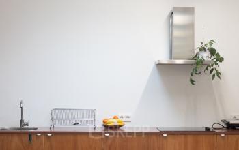Stijlvolle kantoorruimte huren in Amsterdam West met houten meubels en een minimalistisch ontwerp, voorzien van natuurlijk licht door dakramen, ideaal voor creatieve werkprocessen.