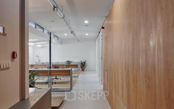 Moderne kantoorruimte huren in een licht gebouw op Hondiusstraat 7H, Amsterdam West. Houten panelen en ventilatiebuizen zijn zichtbaar met een open indeling.