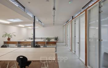 Kantoorruimte huren op Hondiusstraat 7H, Amsterdam West. Moderne open kantoorindeling met ruime werkplekken, veel natuurlijk licht en groene accenten. Ideaal voor professionals die een inspirerende werkomgeving zoeken.