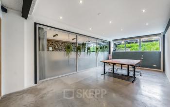 Moderne kantoorruimte huren, gelegen aan Bos en Lommerplantsoen 1, Amsterdam West, met glazen wanden en bureaus, geschikt voor werkactiviteiten.