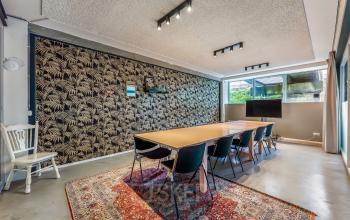 Kantoorruimte huren aan het Bos en Lommerplantsoen 1 in Amsterdam West met een stijlvolle vergaderruimte, gedecoreerd met een patroonbehang en houten tafel, geschikt voor zakelijke bijeenkomsten.