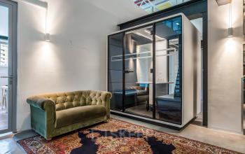 Kantoorruimte huren aan Bos en Lommerplantsoen 1 in Amsterdam West met moderne inrichting, inclusief comfortabele bank en een afgesloten cabine voor privacy. Geschikt voor diverse zakelijke activiteiten.