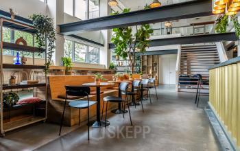 Modern ingerichte kantoorruimte aan Bos en Lommerplantsoen 1, Amsterdam West, met veel natuurlijk licht en planten, geschikt voor verhuur.