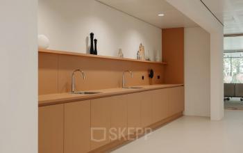 Moderne pantry met bruin-oranje kasten en dubbele wasbak in kantoorpand aan Nachtwachtlaan 20, Amsterdam West.