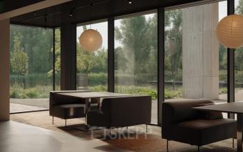 Moderne kantoorruimte aan de Nachtwachtlaan 20 met grote ramen en comfortabele banken, ideaal voor werk en vergaderingen in een groene omgeving.