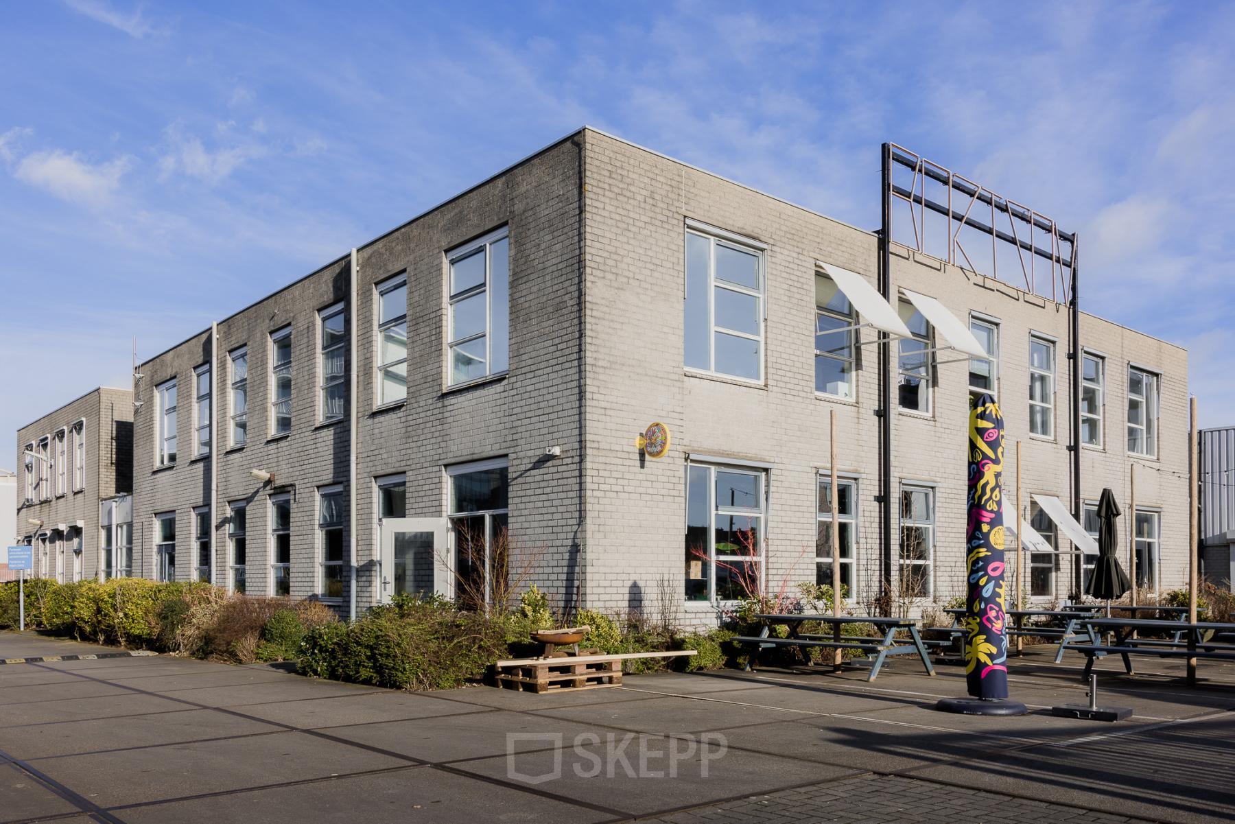 Exterieur van het kantoorpand op Rigakade 10, Amsterdam West, met moderne uitstraling en grote ramen. Beschikbaar voor kantoorruimte huren.