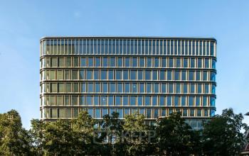 Modern kantoorpand aan het Kon. Wilhelminaplein 4 in Amsterdam West met glazen gevel en omliggende bomen, ideaal voor kantoorruimte huren.