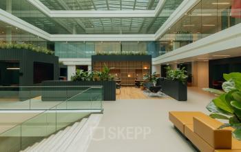 Open en lichte kantoorruimte op Kon. Wilhelminaplein 4, Amsterdam West, met moderne glazen architectuur en planten.