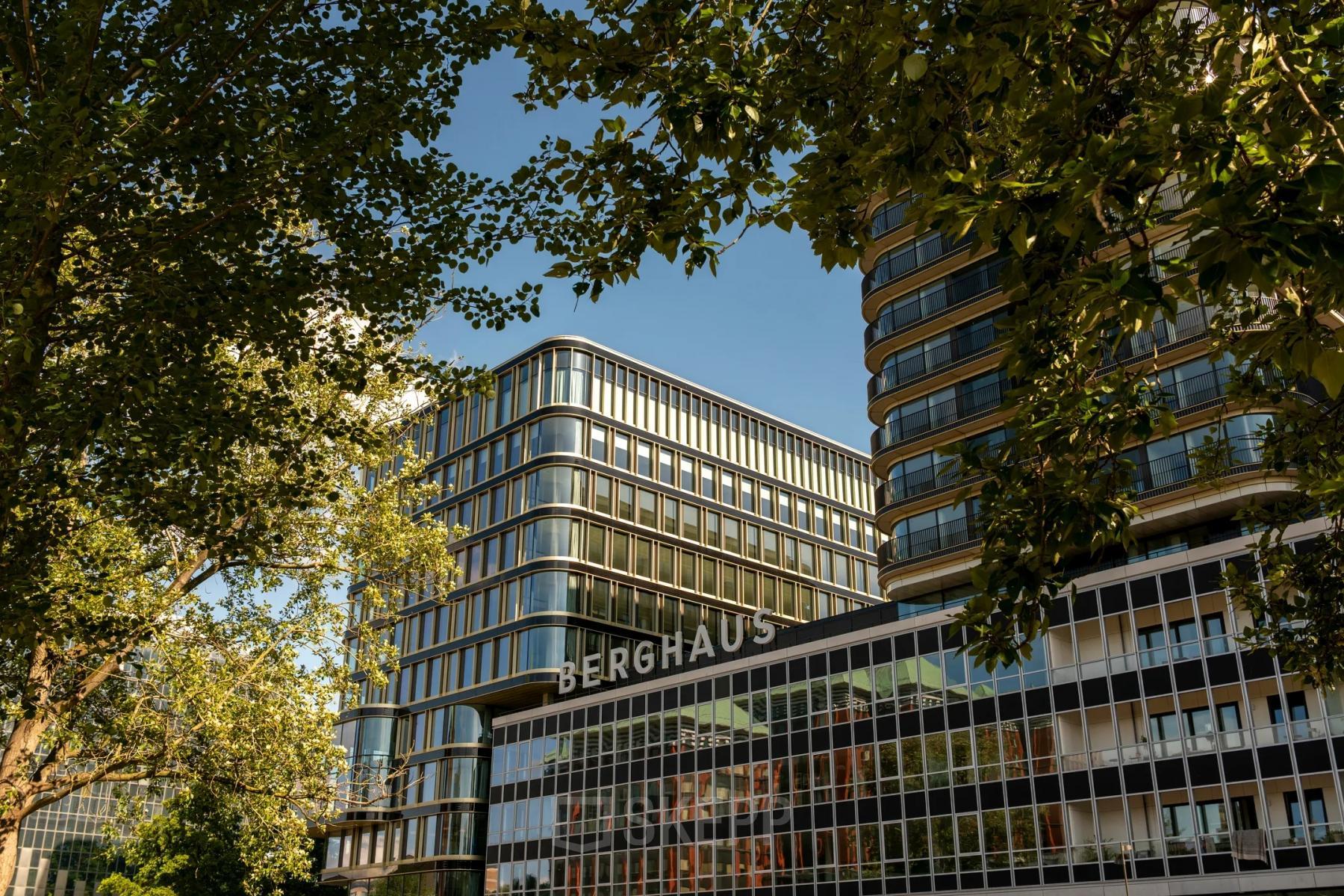 Kantoorpand Berghaus aan het Kon. Wilhelminaplein 4, Amsterdam West, te midden van groene bomen.