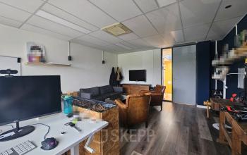 Kantoorruimte huren op Gyroscoopweg 23-25 in Amsterdam Westpoort met moderne meubels, werkplekken, en comfortabele zithoek met flatscreen tv.