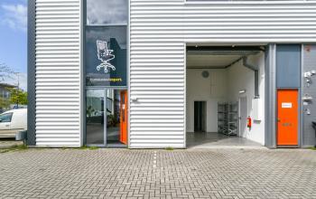 Gebouw Poortland 242 in Amsterdam Westpoort, met zilveren gevel en feloranje deuren. Ruim kantoorpand toegankelijk voor kantoorruimte huren.