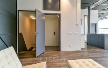 Kantoorruimte huren in het moderne pand op Poortland 242, Amsterdam Westpoort. Interieur toont strakke houten vloeren en minimalistisch design, perfect voor een productieve werkdag.