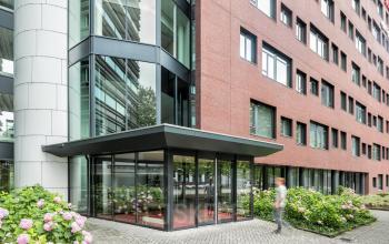 Exterieur van het kantoorpand aan Hullenbergweg 278-308, Amsterdam Zuid-Oost. De moderne glazen entree en de goed onderhouden buitenruimte maken het aantrekkelijk om kantoorruimte te huren.