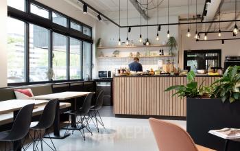 Moderne kantoorpantry met comfortabel zitgedeelte in kantoorpand op Hogehilweg 19, Amsterdam Zuid-Oost, voorzien van houten bar en planten