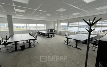 Ruime kantoorruimte te huur op de Laarderhoogtweg 7-19 in Amsterdam Zuid-Oost, met meerdere bureaus en stoelen bij grote ramen voor veel natuurlijk licht.