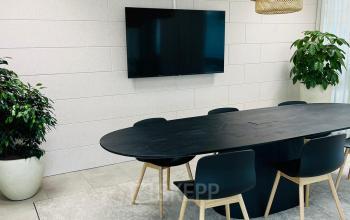 Vergaderruimte met een moderne zwarte tafel, omringd door stoelen, en sfeervolle hanglampen in een kantoorpand aan de Laarderhoogtweg 7-19 in Amsterdam Zuid-Oost.