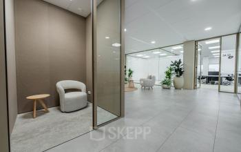 Moderne kantoorruimte in Amsterdam Zuid-Oost met een gemeubileerde wachtruimte, ruime glazen wanden, en meerdere planten voor een frisse uitstraling. Ideaal om te huren op Laarderhoogtweg 7-19.