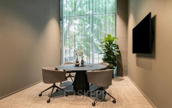 Vergaderruimte in kantoorpand De Entree 201, Amsterdam Zuid-Oost, met ronde tafel, stoelen en groot raam met uitzicht op groen.
