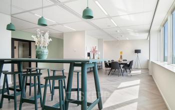 Lichte kantoorruimte in Amsterdam Zuid-Oost bij De Entree 201 met moderne meubels, waaronder hoge tafels en stoelen. Ideaal voor bedrijven die kantoorruimte willen huren.