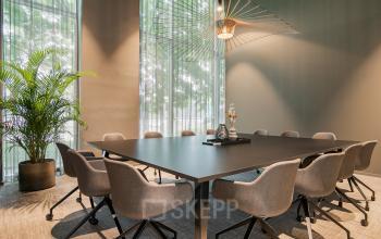 Stijlvolle vergaderruimte met moderne stoelen, grote vierkante tafel en unieke plafondlamp, ideaal voor kantoorruimte huren op De Entree 201 in Amsterdam Zuid-Oost.