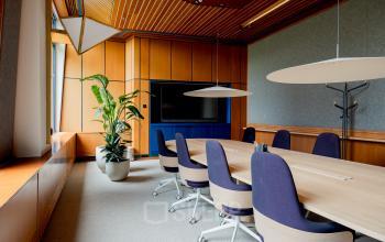 Ruime vergaderruimte in Amsterdam Zuid-Oost met houten panelen en een lange tafel met stoelen, ideaal voor kantoorruimte huren op Bijlmerplein 888.