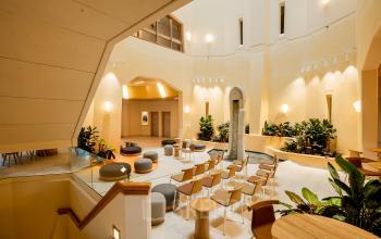 Ruime, lichte kantoorruimte met zitplaatsen en tafels, omgeven door planten, geschikt voor diverse zakelijke activiteiten. Ideaal voor wie een kantoorpand wil huren in Amsterdam Zuid-Oost.