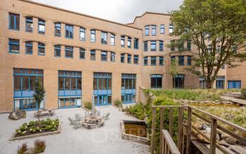 Exterieur van een kantoorpand op Bijlmerplein 888, Amsterdam Zuid-Oost, met een groene, betegelde buitenruimte. Ideaal voor kantoorruimte huren.