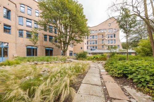 Buitenzijde van een kantoorpand aan Bijlmerplein 888 in Amsterdam Zuid-Oost, omgeven door een groene tuin met een wandelpad.