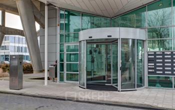 Modern kantoorpand aan De Entree 230-266 in Amsterdam Zuid-Oost met glazen ingang en draaideur, ideaal voor bedrijven die kantoorruimte willen huren.