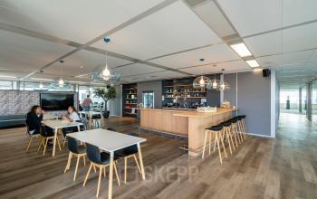 Kantoorruimte huren in een moderne setting in Amsterdam Zuid-Oost. Het kantoorpand aan De Entree 230-266 heeft een stijlvolle inrichting met werkende personen aan tafels. De ruimte ademt een professionele sfeer.