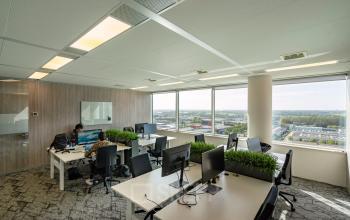 Kantoorruimte huren op De Entree 230-266 in Amsterdam Zuid-Oost met moderne inrichting en grote ramen met uitzicht op de stad. Mensen werken aan bureaus in een open floorplan.