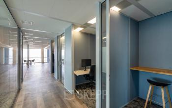 Modern kantoorpand in Amsterdam Zuid-Oost met glazen wanden en gemeubileerde werkplekken, ideaal voor kantoorruimte huren.