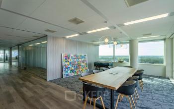 Moderne kantoorruimte huren op De Entree 230-266 in Amsterdam Zuid-Oost met stijlvolle meubels, ruime vergadertafel en glaswanden die een lichte en open sfeer creëren.
