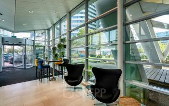 Moderne kantoorruimte aan De Entree 230-266 in Amsterdam Zuid-Oost, met grote ramen die veel licht binnenlaten, comfortabele stoelen en een uitnodigende sfeer. Perfect voor wie kantoorruimte wil huren.