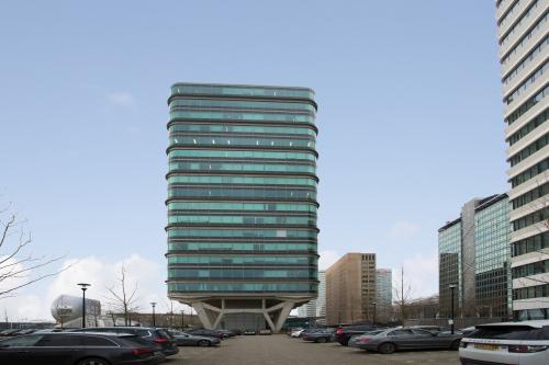 Modern kantoorgebouw met glasgevels gelegen op De Entree 230-266 in Amsterdam Zuid-Oost. Omringd door geparkeerde voertuigen.