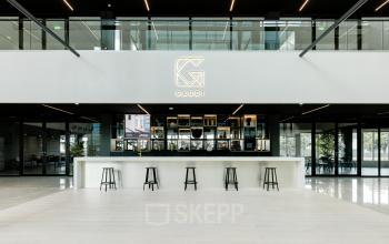 Moderne kantoorlobby op Herikerbergweg 288, Amsterdam Zuid-Oost met een stijlvolle ontvangstbalie en hoge krukken, ideaal voor wie kantoorruimte wil huren.