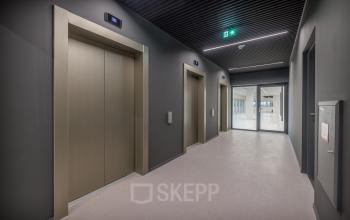 Liftlobby in kantoorpand op Herikerbergweg 288, Amsterdam Zuid-Oost, biedt toegang tot moderne kantoorruimte huren met minimalistische afwerking en ruime doorgang.