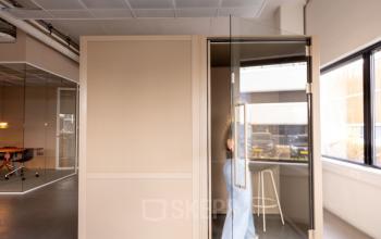 Kantoorruimte huren aan de Luttenbergweg 8 in Amsterdam Zuid-Oost met moderne glazen cabine in een strakke, lichte omgeving. Ideaal voor focus en creativiteit.