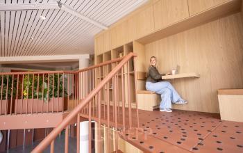 Moderne kantoorruimte op Luttenbergweg 8 in Amsterdam Zuid-Oost met houten interieur en zitgedeelte. Een persoon werkt aan een laptop. Geschikt voor kantoorruimte huren.