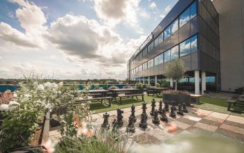 Moderne kantoorgevel met grote glazen ramen en een dakterras met schaakbord op Luttenbergweg 8 in Amsterdam Zuid-Oost. Ideale plek voor kantoorruimte huren met uitzicht en ontspanningsmogelijkheden.
