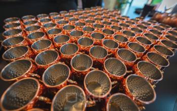 Rijen met koperen mokken op een tafel in een kantoorruimte op Luttenbergweg 8, Amsterdam Zuid-Oost, geschikt voor creatieve bijeenkomsten of evenementen.