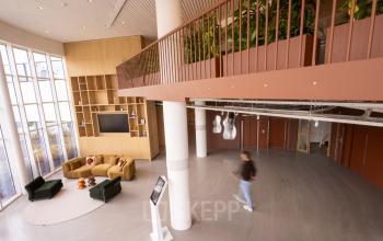 Kantoorruimte huren op Luttenbergweg 8, Amsterdam Zuid-Oost met een moderne, lichte lounge en uitzicht op een mezzanine. Deze ruime werkplek is ideaal voor diverse kantooractiviteiten.